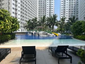 a large swimming pool with two chairs and a slide at Shore occupancy 8 pax cooking balcony Netflix pools MOA Airport Casino PICC马尼拉MOA高级酒店公寓 in Manila