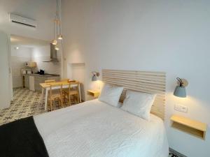 a bedroom with a white bed and a kitchen at Torre de la Yerba in Cáceres