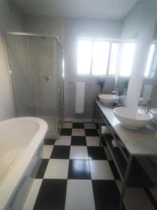 La salle de bains est pourvue de 2 lavabos, d'une baignoire et d'une douche. dans l'établissement @Derricks Luxury Apartments, à Johannesbourg