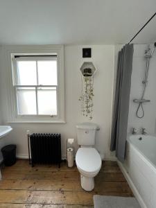 a bathroom with a toilet and a tub and a window at Room In Hackney in London
