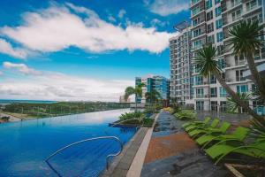 a swimming pool with palm trees and a building at Mactan Newtown Studio Unit Near Airport in Punta Engaño