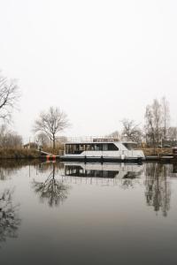 un bateau est amarré à un quai sur une rivière dans l'établissement Deine schwimmende Auszeit auf dem Wasser -Festlieger Hausboot Tobago, à Dömitz