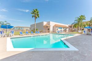 einen Pool mit Stühlen und Sonnenschirmen in einem Resort in der Unterkunft Baymont by Wyndham Port Arthur - Groves Area in Port Arthur