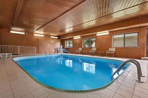 uma grande piscina num quarto de hotel com mesas e cadeiras em Baymont by Wyndham Waterloo em Waterloo