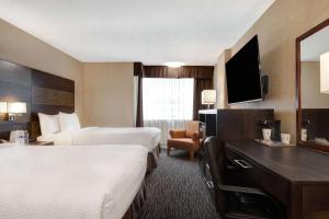 a hotel room with two beds and a television at Days Inn by Wyndham Calgary South in Calgary