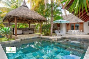 a swimming pool with a umbrella and a house at Oasis 1 Villa Tropicale in Grand-Baie