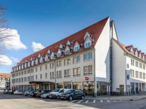 un gran edificio con coches estacionados en un estacionamiento en ibis Hotel Erfurt Altstadt, en Erfurt
