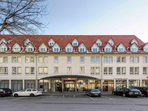 un gran edificio con coches estacionados en un estacionamiento en ibis Hotel Erfurt Altstadt, en Erfurt