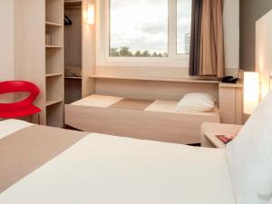 um quarto com uma cama, uma janela e uma cadeira vermelha em ibis Montevideo Rambla em Montevidéu