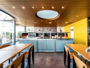 a large kitchen with blue cabinets and wooden tables at ibis Montevideo Rambla in Montevideo