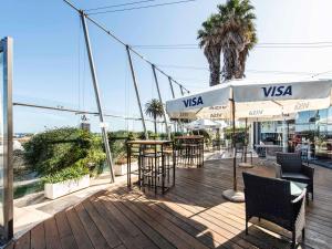 eine Terrasse mit Tischen und Sonnenschirmen auf einer Terrasse in der Unterkunft ibis Montevideo Rambla in Montevideo