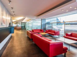 a lobby with red chairs and tables in a building at ibis Montevideo Rambla in Montevideo