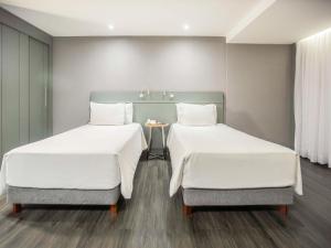 2 Betten in einem Zimmer mit einem Tisch dazwischen in der Unterkunft Grand Mercure Brasilia Eixo Monumental in Brasilia