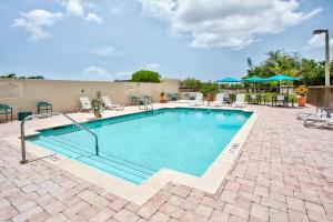 Hampton Inn & Suites Cape Coral / Fort Myers في كيب كورال: مسبح كبير مع كراسي ومظلات