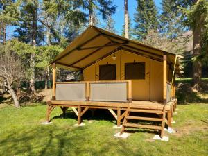 una casa amarilla en una plataforma de madera en el césped en Camping Chantemerle en Bédouès