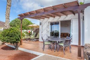 a patio with a table and chairs under a pergola at Jardines del Sol in Playa Blanca
