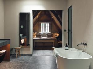 een badkamer met een bad en een slaapkamer met een bed bij Botanic Sanctuary Antwerp - The Leading Hotels of the World in Antwerpen