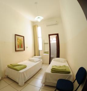 een kamer met 2 bedden en een stoel. bij Grande Hotel Renascença in Juiz de Fora