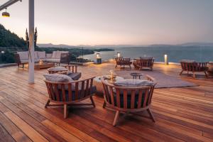 a deck with chairs and tables and a view of the water at Angsana Corfu Resort & Spa in Benitses