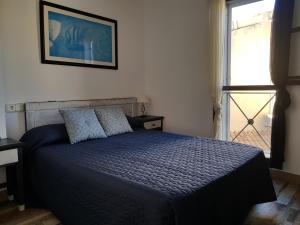 a bedroom with a bed with a blue comforter and a window at Casa Dúplex en Puerto de Alcudia in Alcudia
