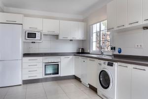 a kitchen with white cabinets and a washer and dryer at Jardines del Sol in Playa Blanca
