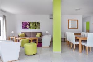 uma sala de estar com um sofá, mesas e cadeiras em Jardines del Sol em Playa Blanca