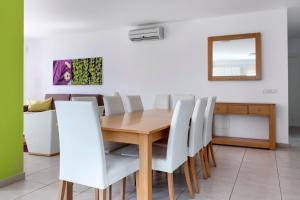 a dining room with a wooden table and white chairs at Jardines del Sol in Playa Blanca