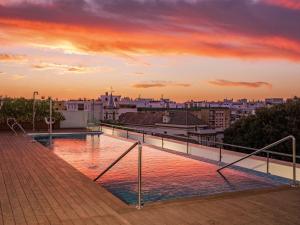 a swimming pool on the roof of a building at sunset at Ibis Styles Sevilla City Santa Justa in Seville