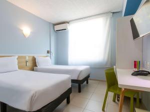 a room with two beds and a desk and a window at ibis Styles Manaus in Manaus