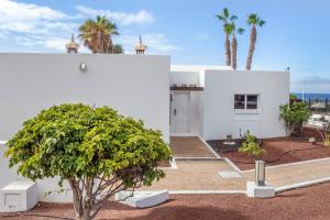 a white house with a tree in front of it at Jardines del Sol in Playa Blanca