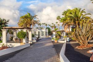 a resort with palm trees and a cobblestone street at Jardines del Sol in Playa Blanca