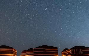 a starry night with buildings in the foreground at Bedouin bunch camp in Wadi Rum
