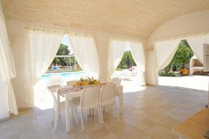 een witte eetkamer met een tafel en stoelen bij trullo lantane in San Michele Salentino