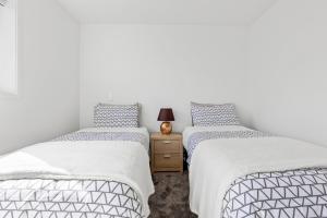 Habitación con 2 camas individuales y paredes blancas. en Beachside Townhouse, en Christchurch