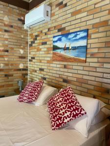 - un lit avec deux oreillers et un tableau sur un mur en briques dans l'établissement Pousada Anjo da Guarda, à Guarda do Embaú