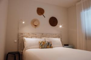 ein Schlafzimmer mit einem weißen Bett mit Hüten an der Wand in der Unterkunft ROTA - Opo airport house in Maia