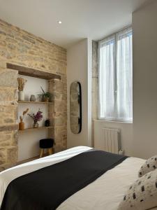 een slaapkamer met een groot bed en een stenen muur bij La Cabotte - Confort & Charme au Centre Historique - Balcon sur cour in Dijon