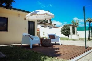 twee stoelen en een parasol op een houten terras bij ROTA - Opo airport house in Maia