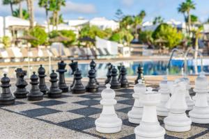a chess board in front of a swimming pool at Jardines del Sol in Playa Blanca