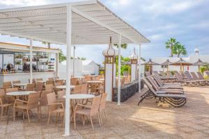 a patio with tables and chairs and a bar at Jardines del Sol in Playa Blanca