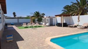 einen Pool in einem Garten mit Stühlen und einem Zaun in der Unterkunft Villa Experience Heated Salty Water Pool in Caleta de Fuste