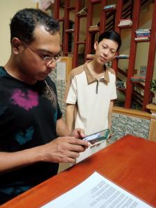 deux hommes debout à côté d'une table en regardant un téléphone portable dans l'établissement Newway Homestay Ninh Bình, à Ninh Binh