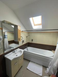 a bathroom with a tub and a sink and a mirror at Sara’S Apartament in Suceava