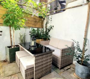 an outdoor seating area with wicker chairs and a table at Spacious & Renovated 1-Bed Garden Flat in London in London