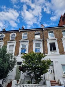 a large brick building with white windows and a tree at Spacious & Renovated 1-Bed Garden Flat in London in London