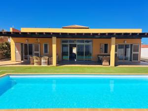 a house with a swimming pool in front of it at VILLA PARADISE in La Guirra +15 photos
