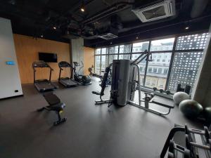 einen Fitnessraum mit Kardiogeräten in einem Zimmer mit Fenster in der Unterkunft Katowice Sokolska Towers in Kattowitz