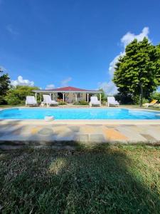 a swimming pool with two chairs and a house at 971B - La Villa ROUYO, villa créole accessible PMR in Le Moule