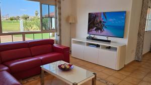 salon z czerwoną kanapą i telewizorem z płaskim ekranem w obiekcie Villa BONITA on Golf in El Descanso ,Caleta Fuste-Fuerteventura w mieście Caleta De Fuste
