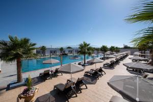 a pool with chairs and umbrellas in a resort at Paradice Hotel Luxury Suites-Near zorbas Beach-FREE Breakfast in Stavros